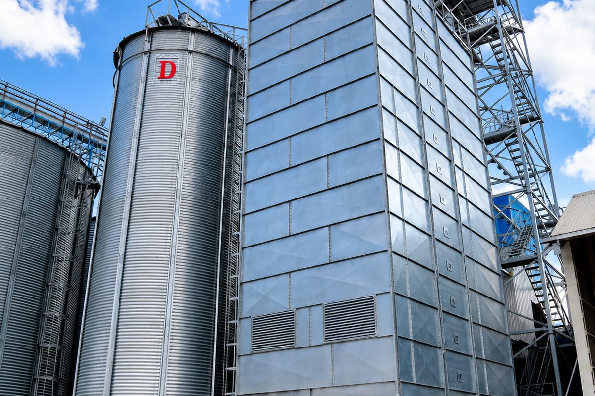 Continuous-flow grain dryer tower beside a storage silo